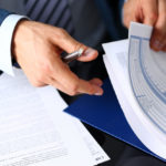 Male arm in suit offer insurance form clipped to pad